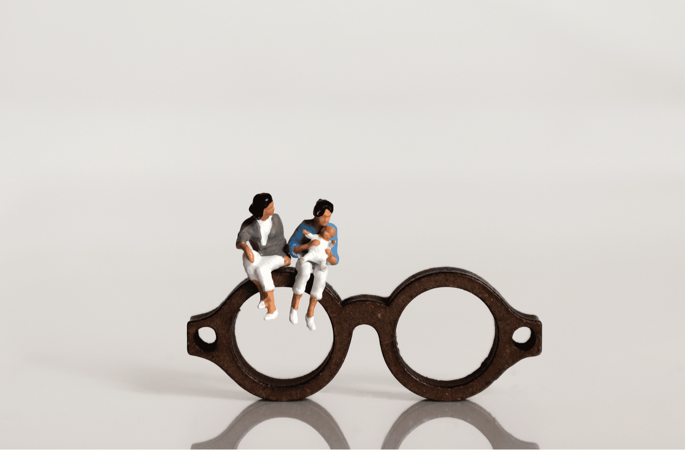 A pair of reading glasses with people sitting on it.