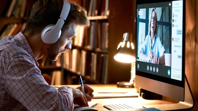 A man taking online classes with headphone and a computer