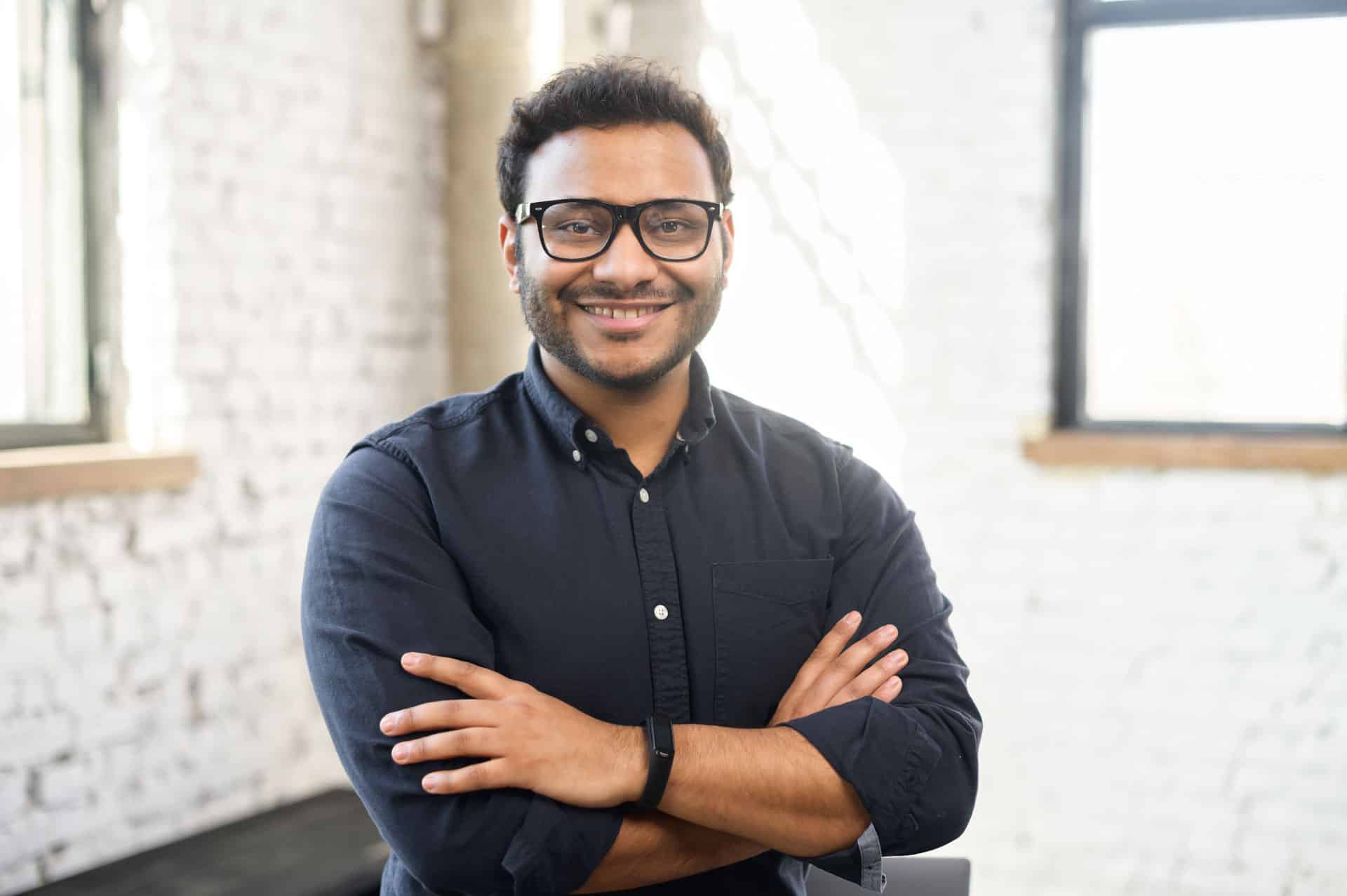 Ambitious Hindu man in smart casual shirt stands with arms crossed