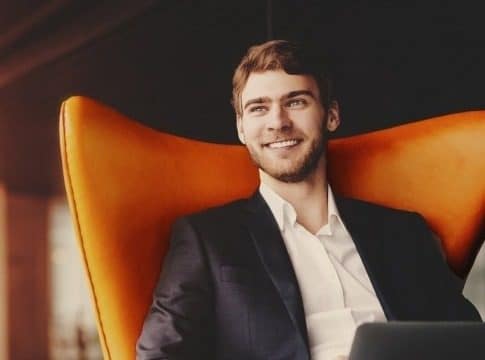A happy man sitting on an orange chair