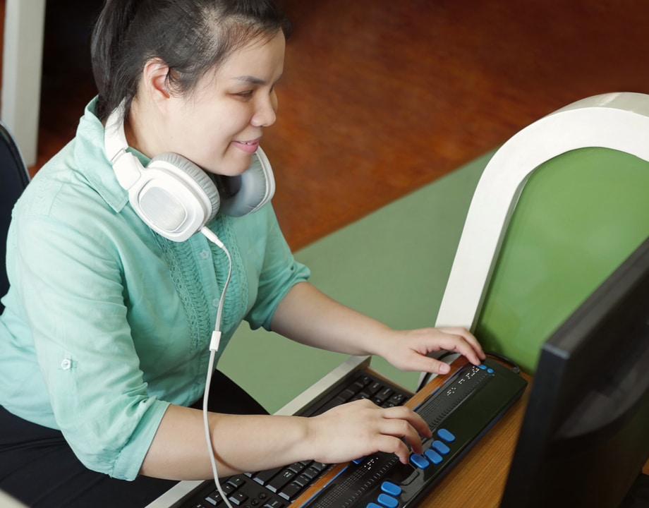 A lady working an a computer with headphones