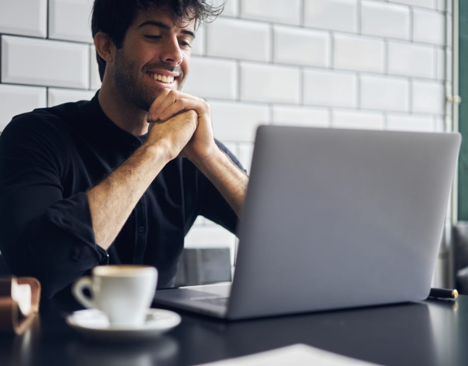 A happy man working on a silver laptop