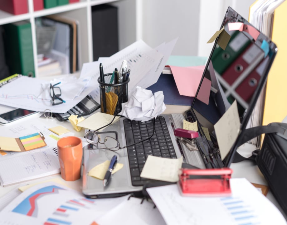 A laptop on a table with with lots of mess