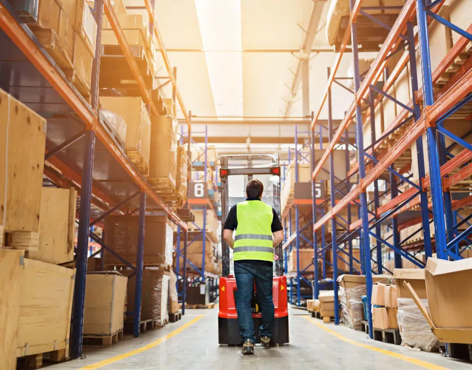 A man walking with a machine in a warehouse