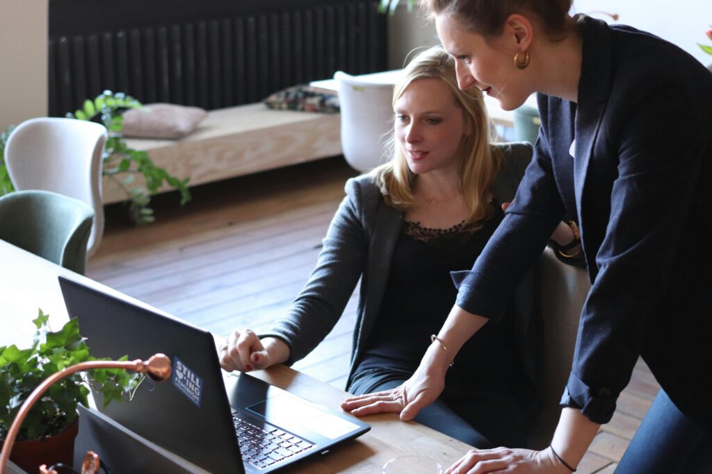 A businesswoman working on a laptop with a man