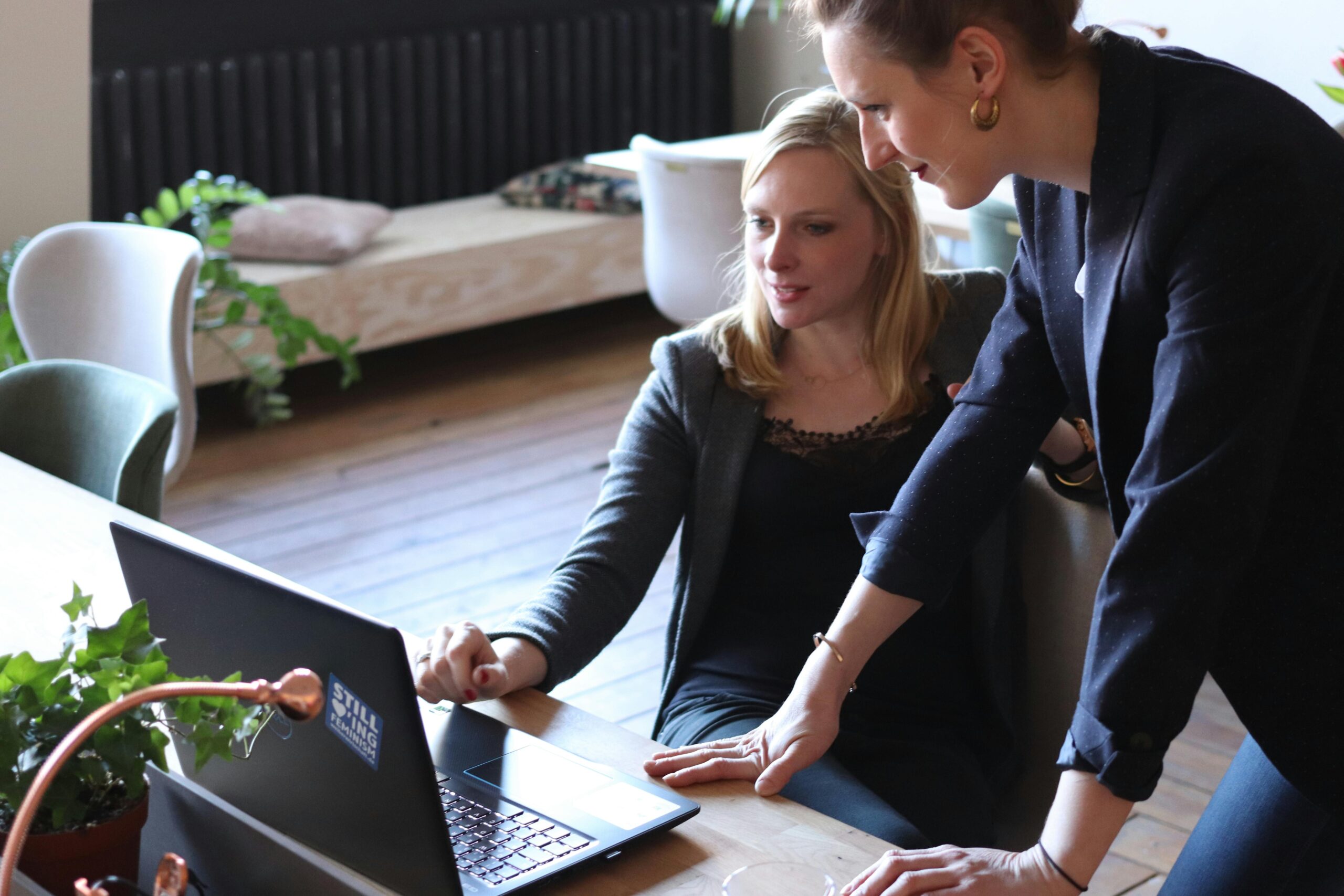 A businesswoman working on a laptop with a man